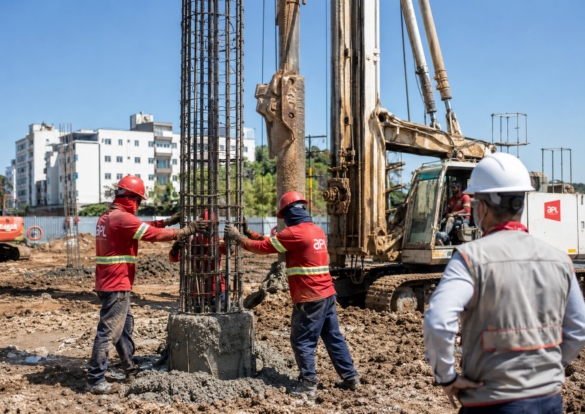 Equipe da APL Engenharia acompanha a introdução da armadura em estaca hélice contínua monitorada, com perfuratriz ao fundo, armadura longitudinal com estribos e controle técnico da execução de fundações profundas.