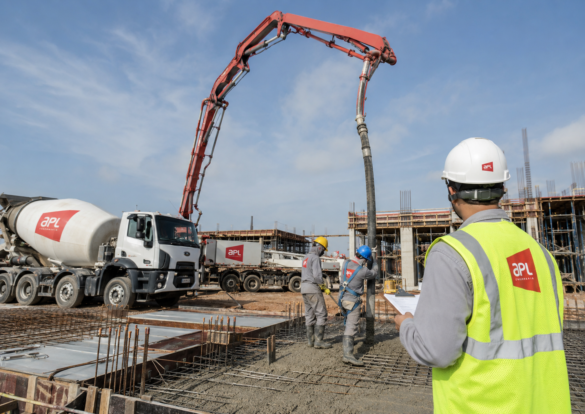 Caminhão betoneira e bomba de concreto lançando concreto usinado em obra, com equipe da APL Engenharia acompanhando o bombeamento de concreto em Montes Claros.